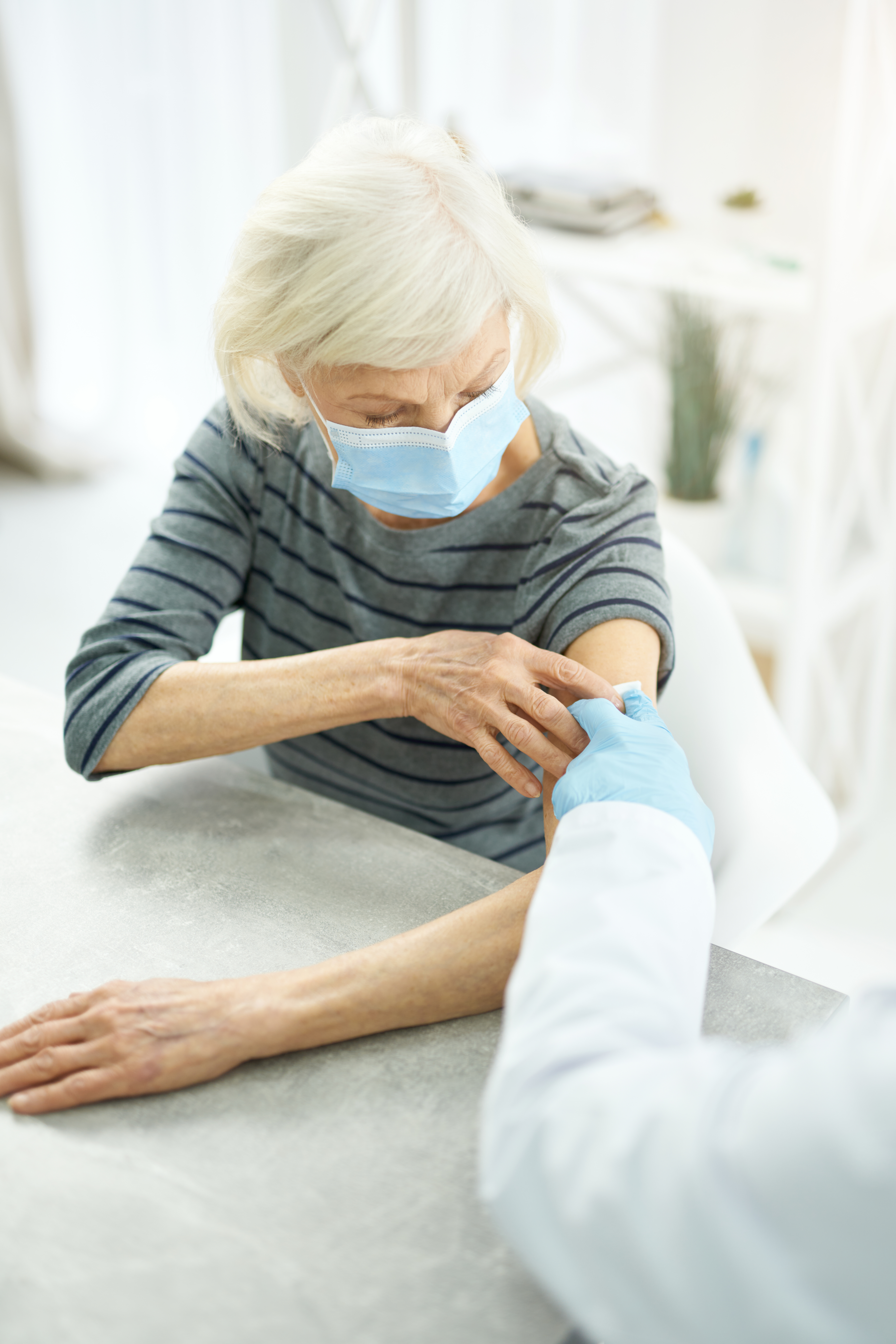 Old woman receiving injection of coronavirus vaccine in clinic